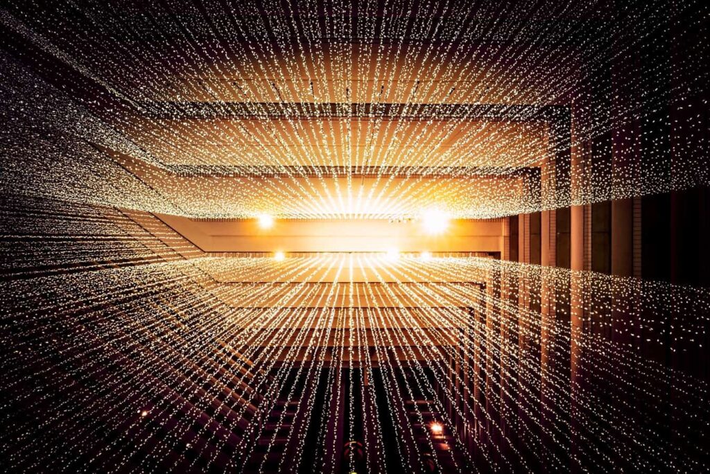 Golden tunnel of glowing light points converging toward a bright vanishing point, abstract digital connectivity concept