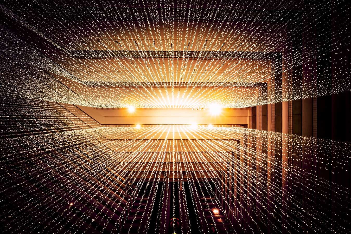 Golden tunnel of glowing light points converging toward a bright vanishing point, abstract digital connectivity concept
