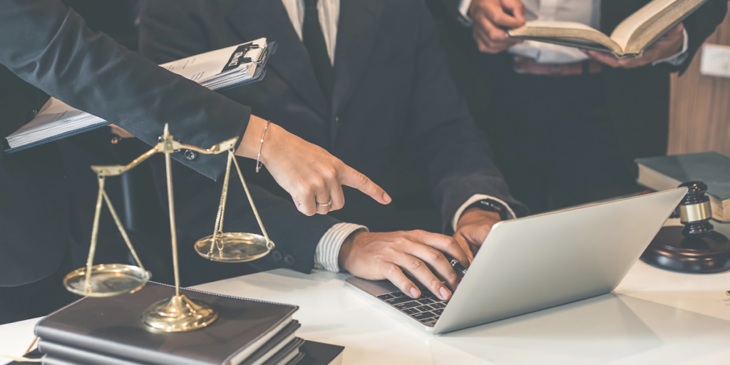Two lawyers at a desk with a laptop and scales of justice, illustrating Google Ads for law firms