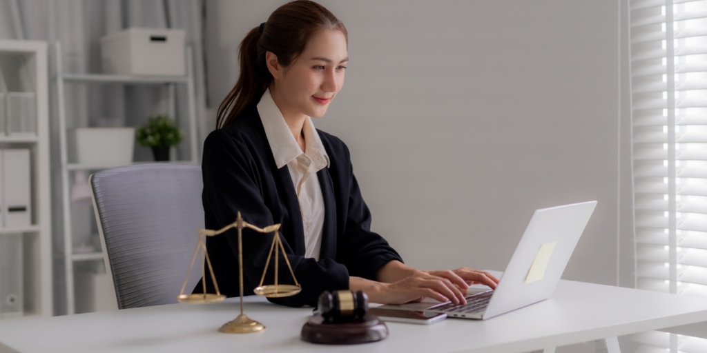 Female lawyer working on laptop at desk with scales of justice and gavel, representing digital marketing for family lawyers