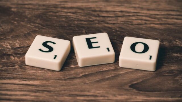 Three Scrabble tiles spelling SEO on a wooden surface, illustrating SEO strategy and technical optimisation