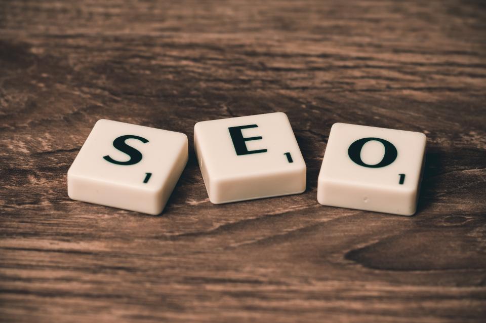 Three Scrabble tiles spelling SEO on a wooden surface, illustrating SEO strategy and technical optimisation