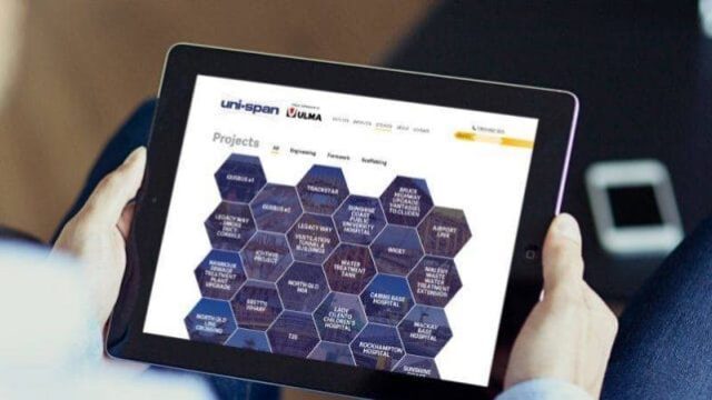 Person holding a tablet displaying the Uni-span projects page with a hexagonal grid layout